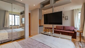 Une chambre d’hôtel moderne avec un grand lit, une télévision, un canapé et un miroir.