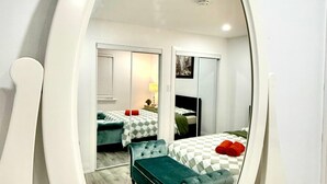 Een slaapkamer met twee bedden, een spiegel en een dressoir.