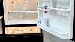 Een open koelkast met meerdere planken en een vriesvak.