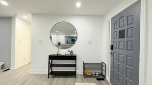 Een moderne badkamer met een ronde spiegel, een zwart wastafelmeubel en een schoenenrek.