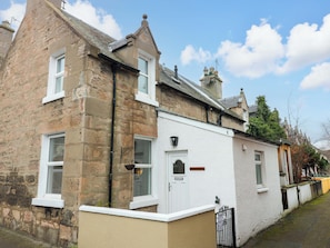 A traditional stone and plaster house with a white door, a small window with shutters, and a number plaque on the wall. - Rose Cottage (Nairn)