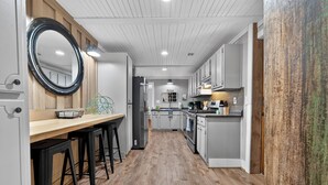 Une cuisine moderne avec un plancher en bois, un mur d’accent en bois et un grand miroir.