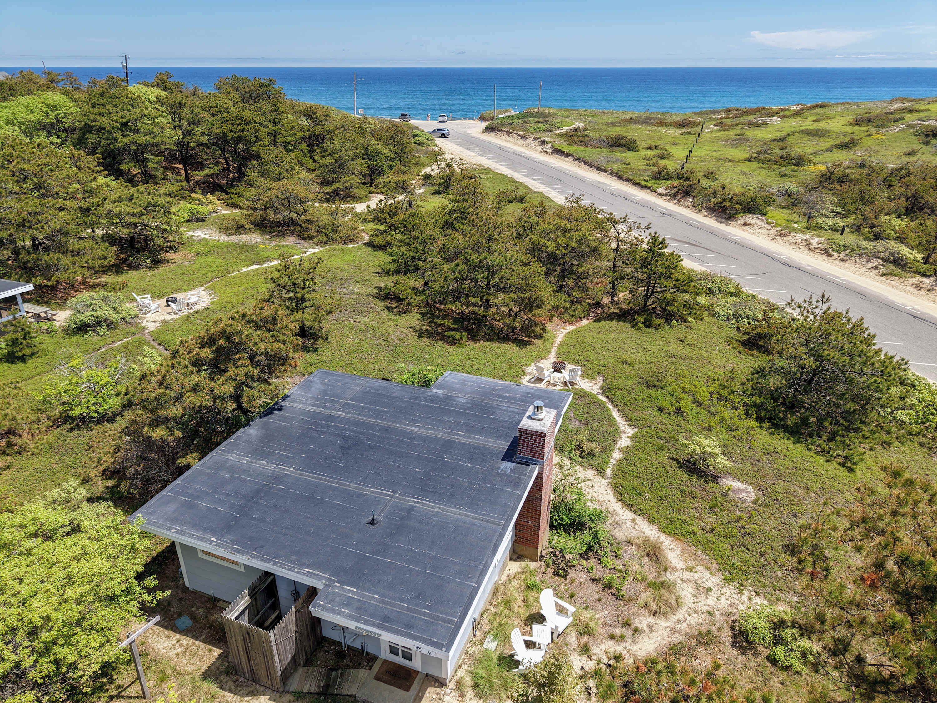 A house with a flat roof, a fenced yard, and a view of the ocean.