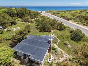 A house with a flat roof, a fenced yard, and a view of the ocean.