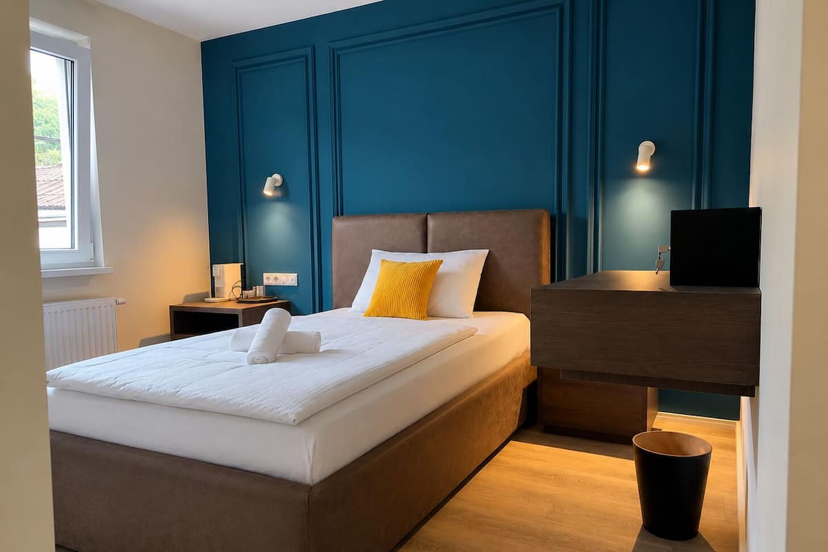 A bedroom with a bed, bedside tables, a desk, and a window.