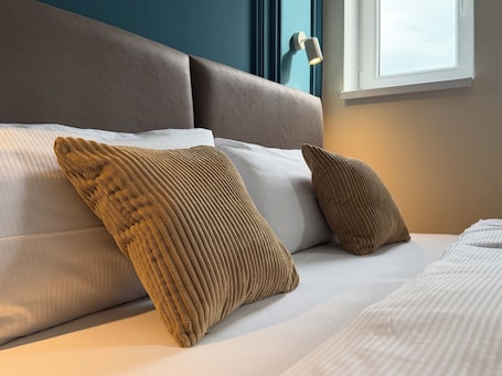 A bed with a headboard, two pillows, and a window.. Hotel Nare