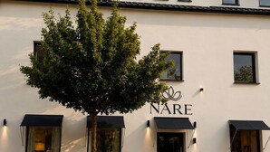 Un edificio de fachada blanca, con un árbol en la parte delantera y el nombre 'NARE' en la entrada.