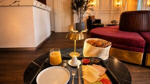 Bandeja de desayuno con cruasanes, queso, tomates y un vaso de zumo de naranja.