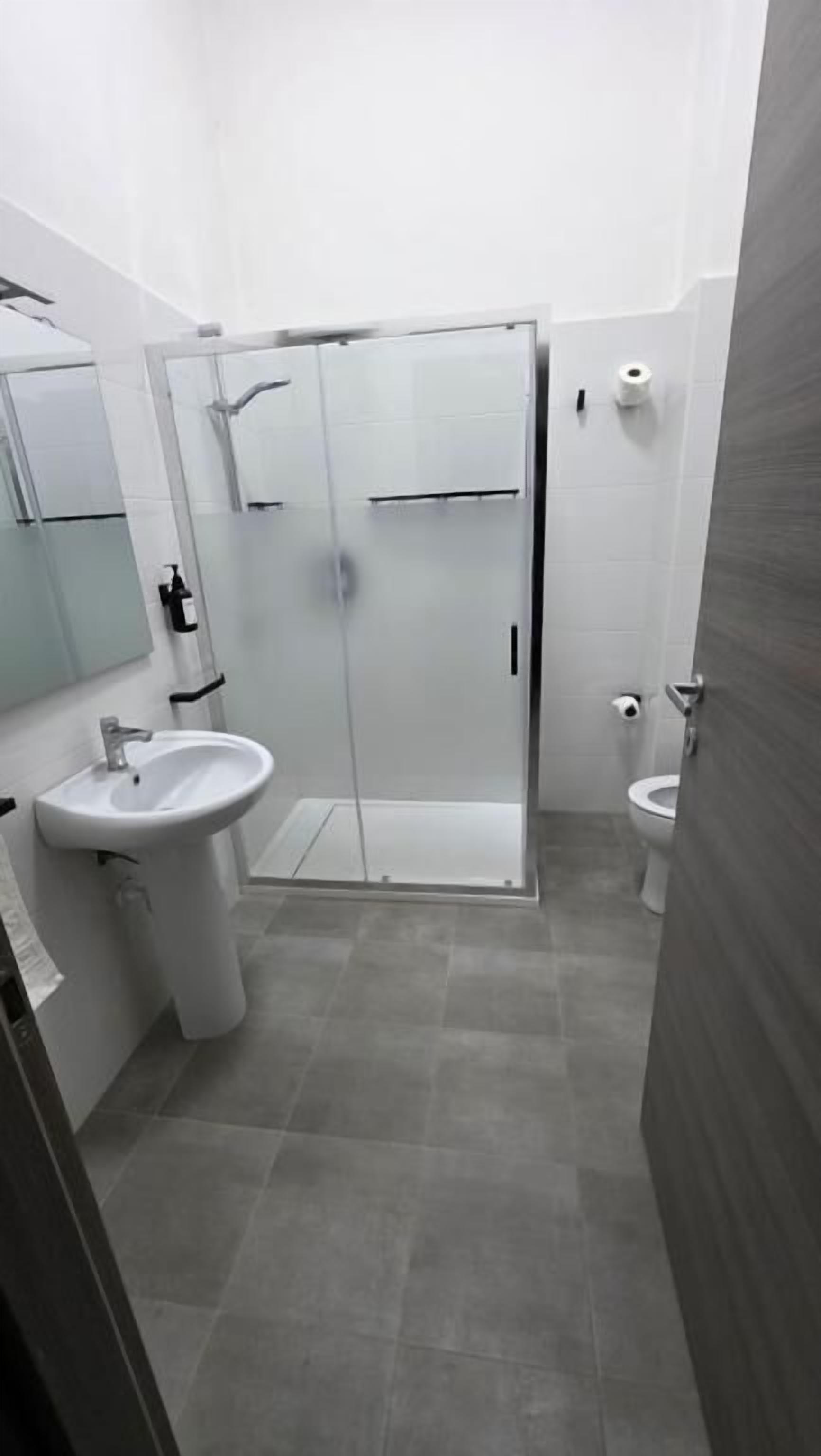 A modern bathroom with a glass shower enclosure, a sink, and a toilet.