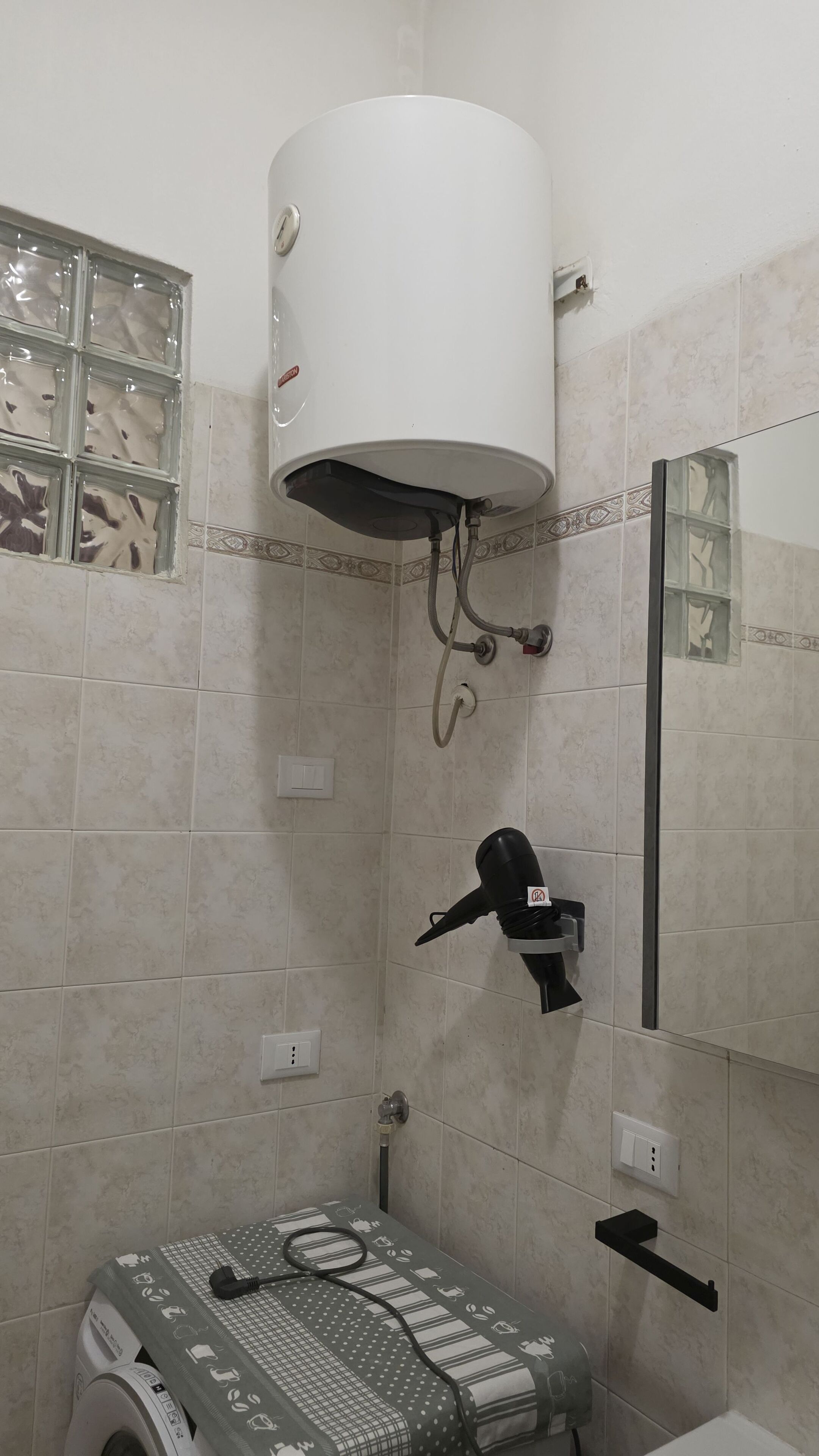 Ein Badezimmer mit einer weißen Toilette, einem Handtuchhalter, einer Duschbrause und einem Spiegel.