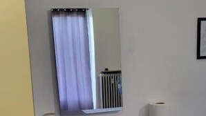 A modern bathroom with a grey vanity, a mirror, a toilet paper roll, and a small white speaker. - Casa Manzoni (Novara)