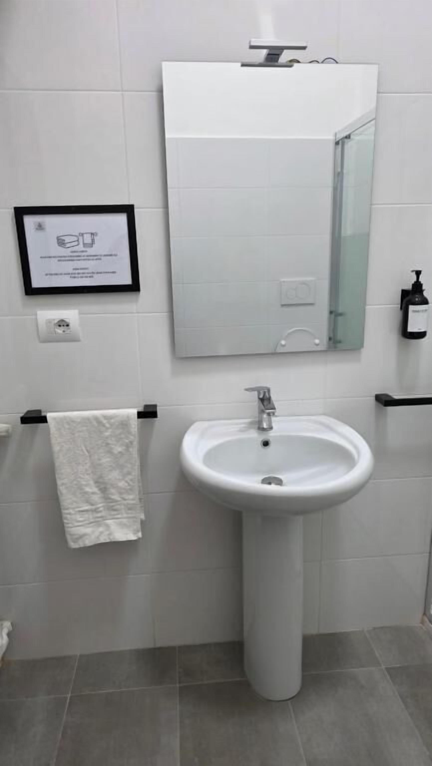 A bathroom with a white sink, a mirror, and a framed certificate on the wall.