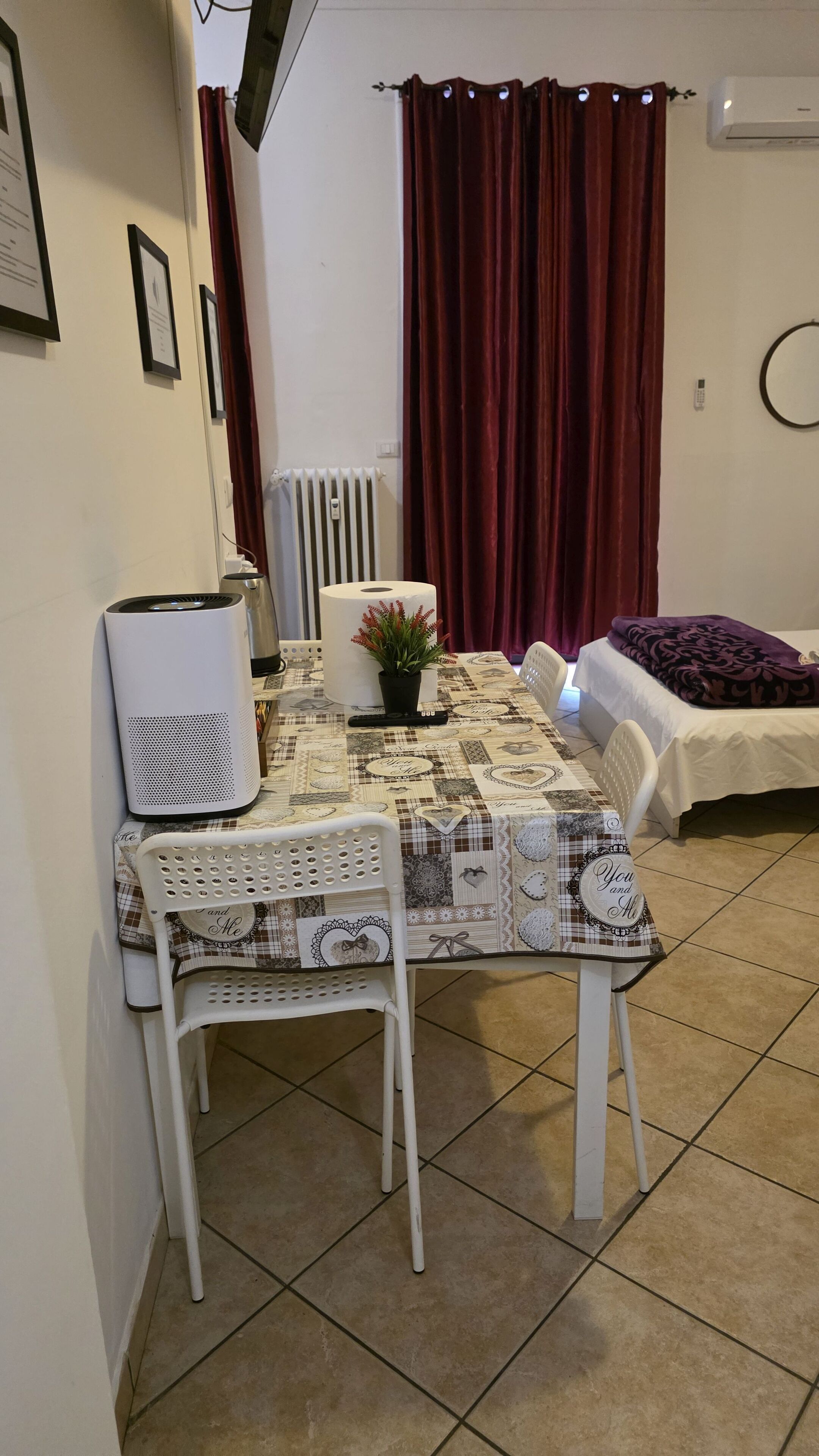 A small, cozy room with a dining table, a chair, a bed, and a radiator.