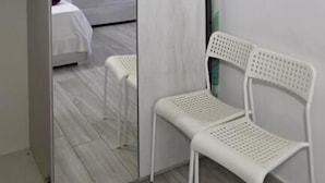 A bedroom with a large mirror, a bed, a white chair, and a wardrobe. - Casa Manzoni (Novara)