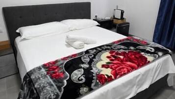 A neatly made bed with a floral bedspread, a white pillow, and a folded white towel.