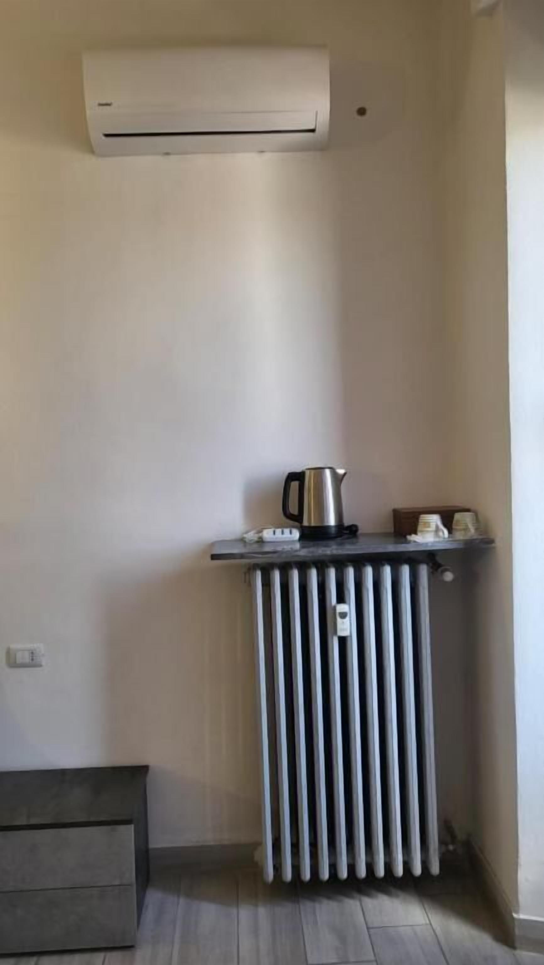 Una kitchenette pequeña con aire acondicionado integrado, un hervidor y un radiador.
