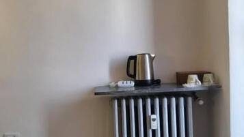 Una kitchenette pequeña con aire acondicionado integrado, un hervidor y un radiador.