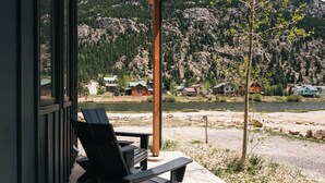 Une vue sur le lac, avec une terrasse en bois, une chaise et un panorama sur les maisons et les montagnes.