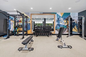 Un gimnasio con equipamiento de levantamiento de pesas, mancuernas y máquinas de ejercicio.