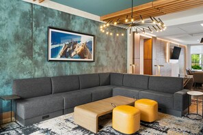 A modern living room with a sectional sofa, a coffee table, and a unique pendant light. - Hampton Inn By Hilton Aiken (Aiken)