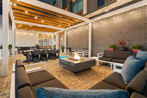An outdoor seating area with a fire pit, lounge chairs, and a brick wall. - Hampton Inn By Hilton Aiken (Aiken)