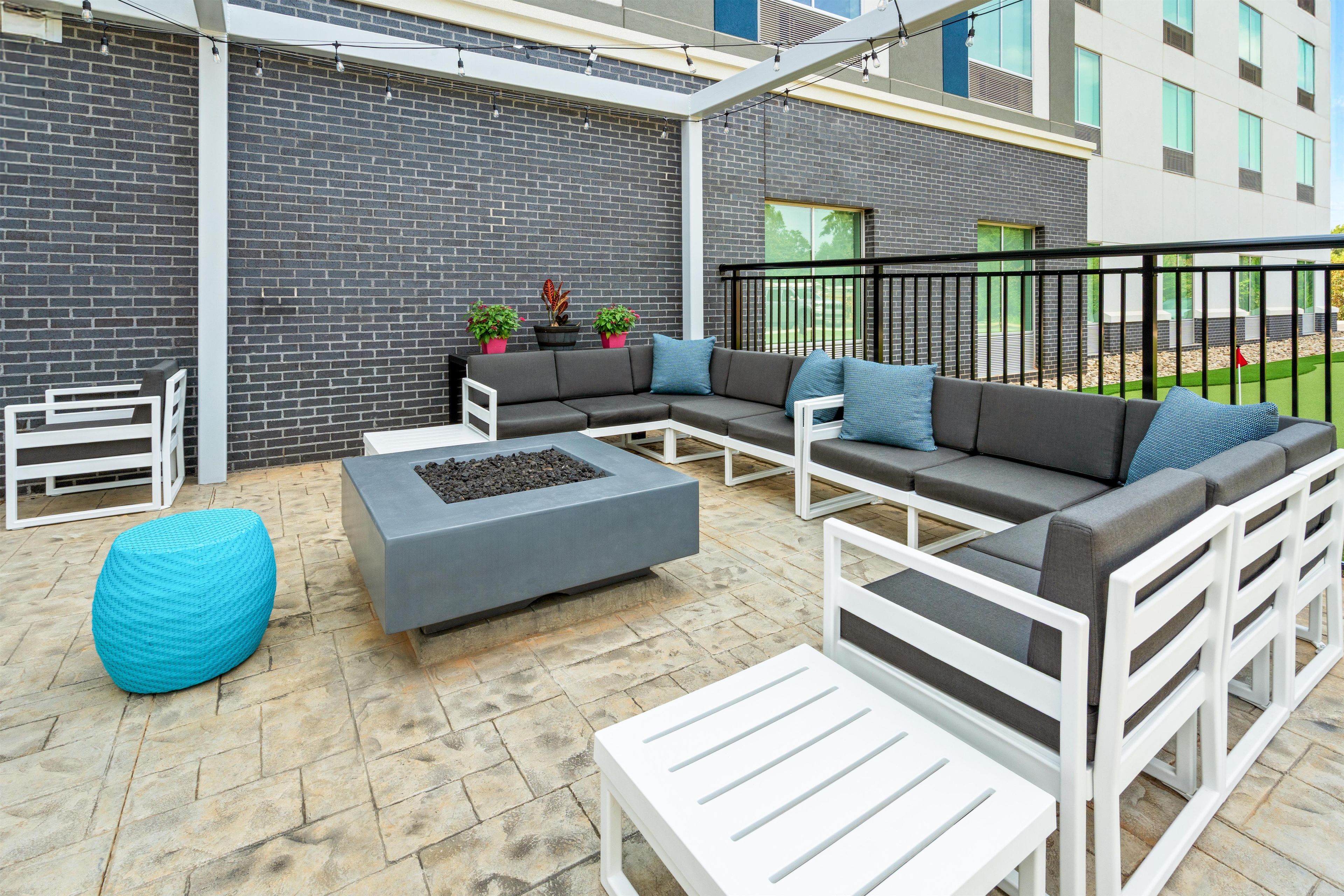 Une terrasse extérieure avec un canapé modulable, une table basse et un pouf bleu.