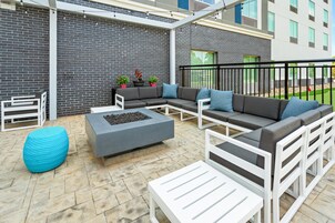 An outdoor patio with a sectional sofa, a coffee table, and a blue pouf.
