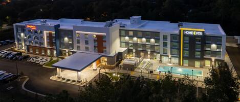 Un hotel moderno con varios pisos, piscina y estacionamiento.
