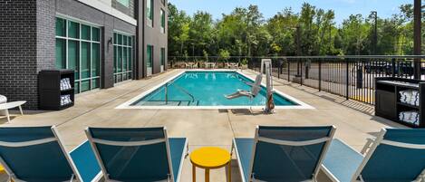 Un área de piscina con sillas de descanso y una piscina.