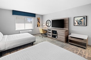Una habitación de hotel con cama, escritorio, televisor y ventana.