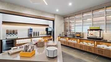 A modern breakfast area with self-serve coffee machines, a variety of food options, and a clean, organized layout.