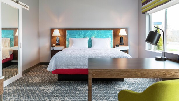 A hotel room with a bed, bedside tables, a desk, a chair, and a window with curtains. - Hampton Inn By Hilton Aiken (Aiken)