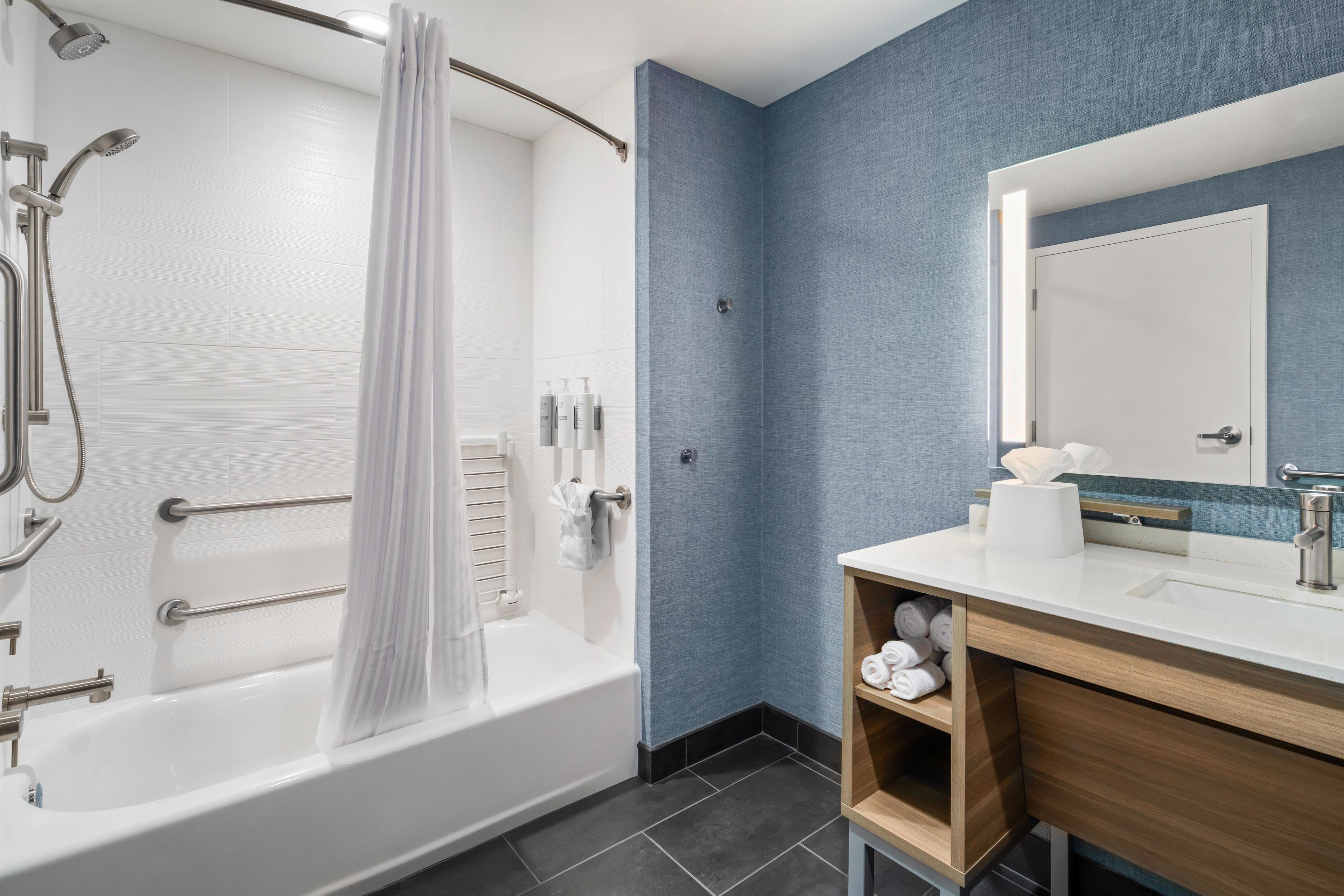 A modern bathroom with a bathtub, shower, and vanity with a mirror.