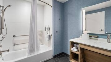 A modern bathroom with a bathtub, shower, and vanity with a mirror.