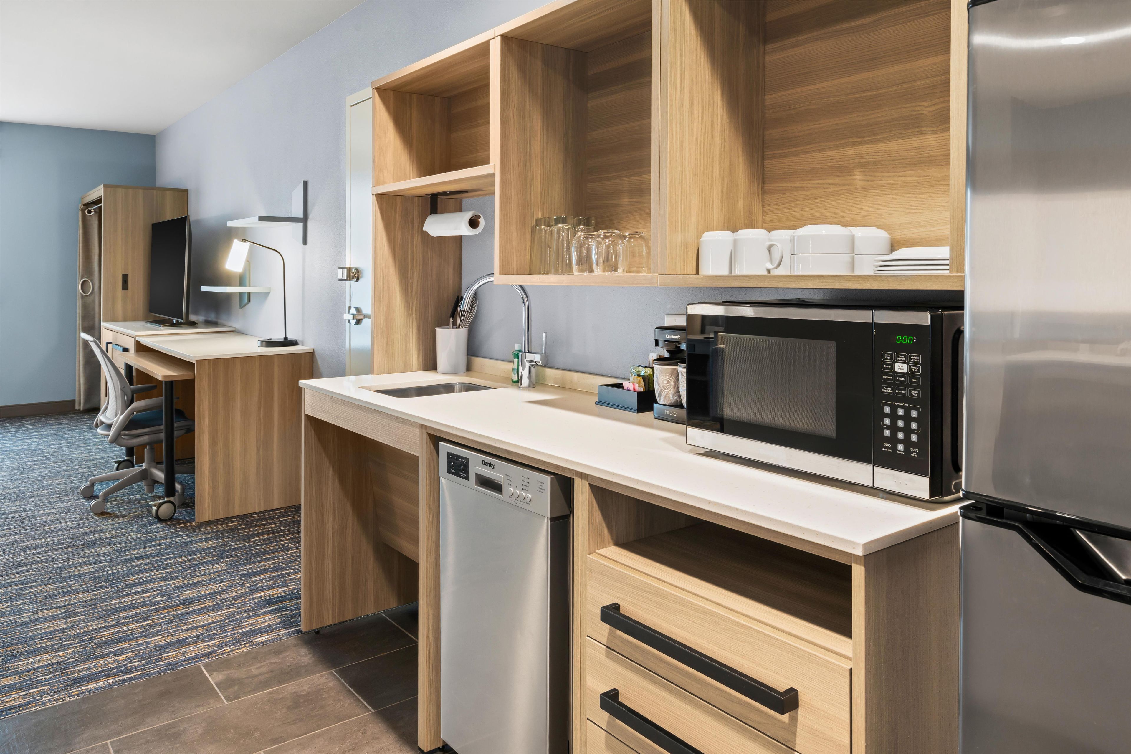 A compact kitchenette with a microwave, coffee maker, and a dishwasher.