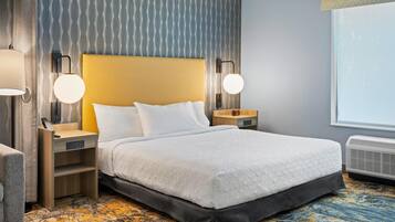 Una habitación de hotel con una cama grande, mesitas de noche, una lámpara, un reloj y una ventana.