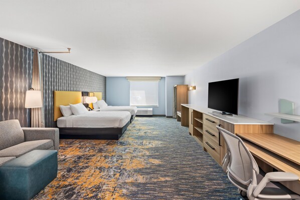 A hotel room with a bed, a desk, a TV, a chair, and a couch. - Home2 Suites By Hilton Aiken (Aiken)