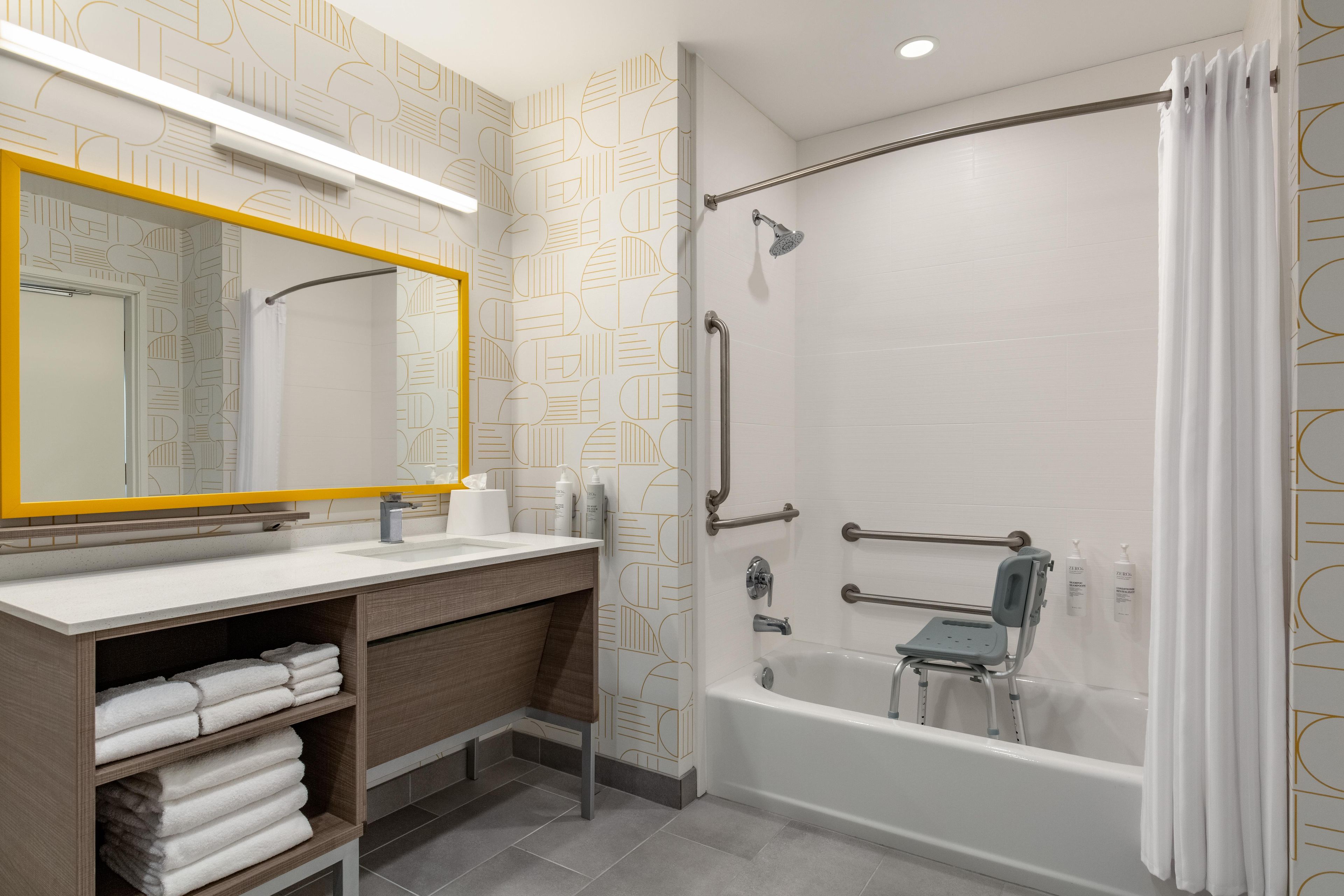 Un baño moderno con ducha, tocador con espejo y un perchero para toallas.