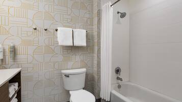 A bathroom with a toilet, a shower, and a towel rack with two towels.