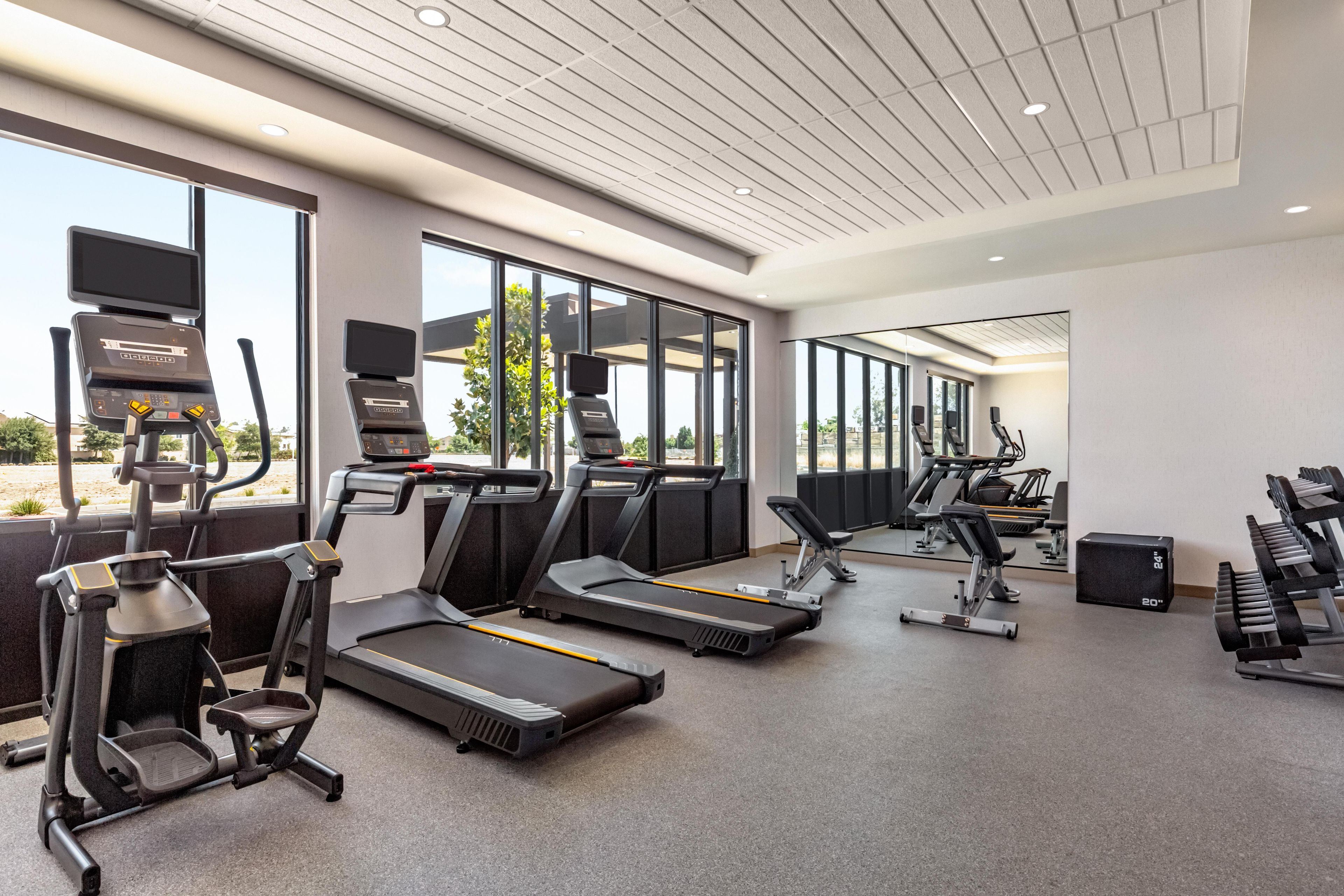 A modern gym with treadmills, elliptical machines, and free weights.