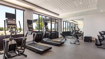 A modern gym with treadmills, elliptical machines, and free weights.