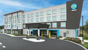 A modern hotel building with a prominent 'tru' logo, a covered entrance, and a landscaped area with planters. - Tru By Hilton Midland East (Midland)