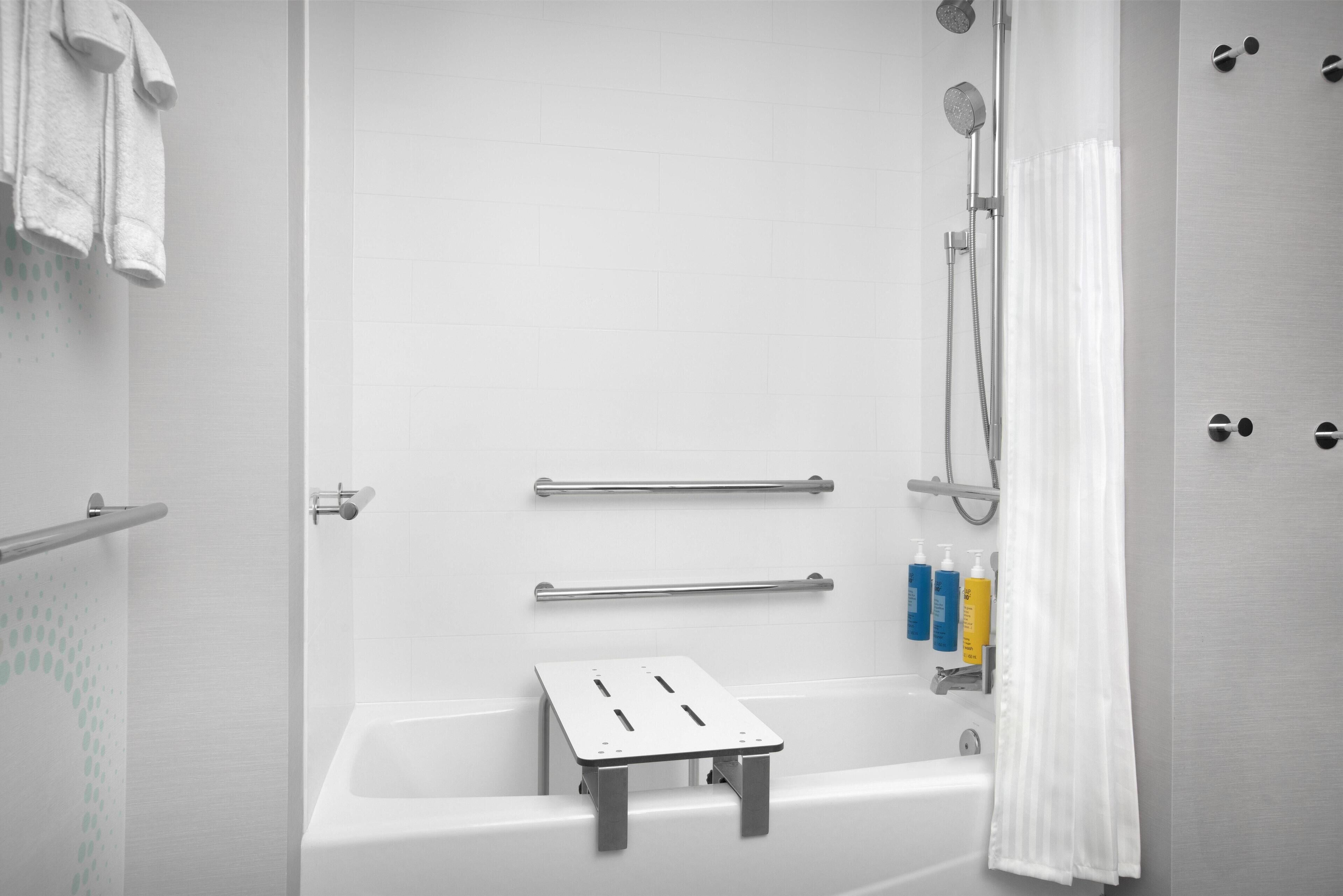 Un bagno moderno con vasca, doccia, maniglie di sostegno e articoli da toilette.