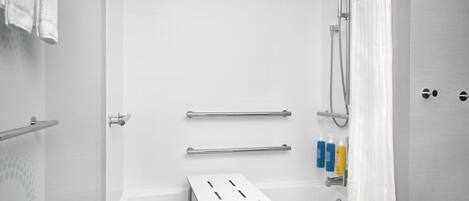 Un bagno moderno con vasca, doccia, maniglie di sostegno e articoli da toilette.