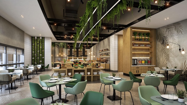 A modern restaurant with green chairs, wooden tables, and hanging plants. - Hilton Garden Inn Bengaluru Embassy TechVillage Outer Ring Road (Bengaluru)