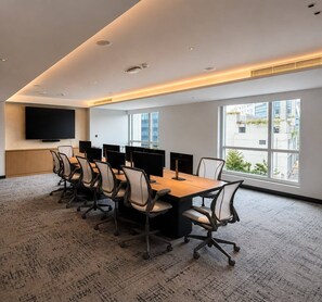 A conference room with a long table, multiple chairs, a flat-screen TV, and large windows with a city view. - Hilton Garden Inn Bengaluru Embassy TechVillage Outer Ring Road (Bengaluru)