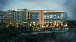A modern hotel with a curved facade, multiple floors, and a well-lit entrance. - Hilton Garden Inn Bengaluru Embassy TechVillage Outer Ring Road (Bengaluru)