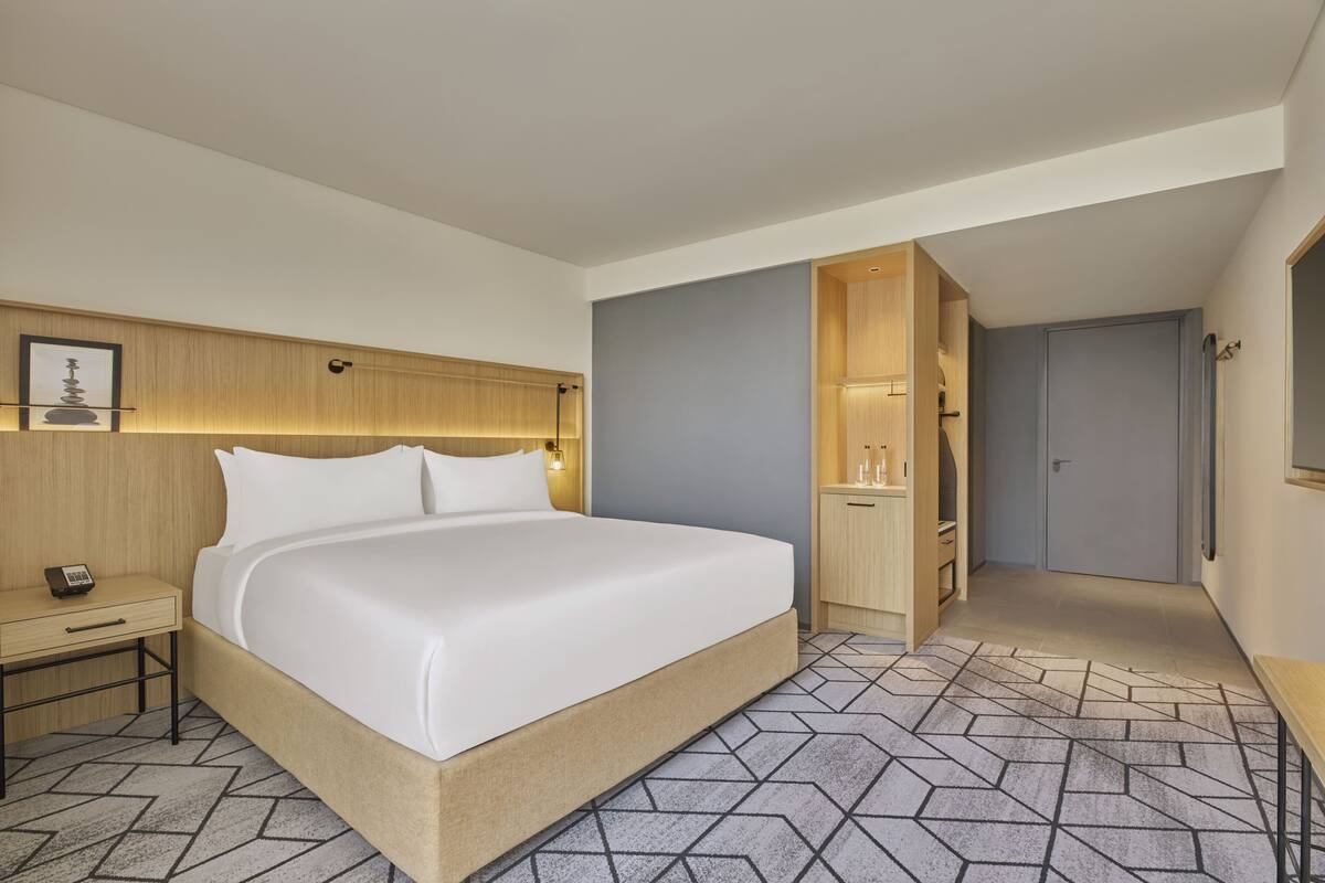 Una habitación de hotel con una cama grande, una mesita de noche y un armario.