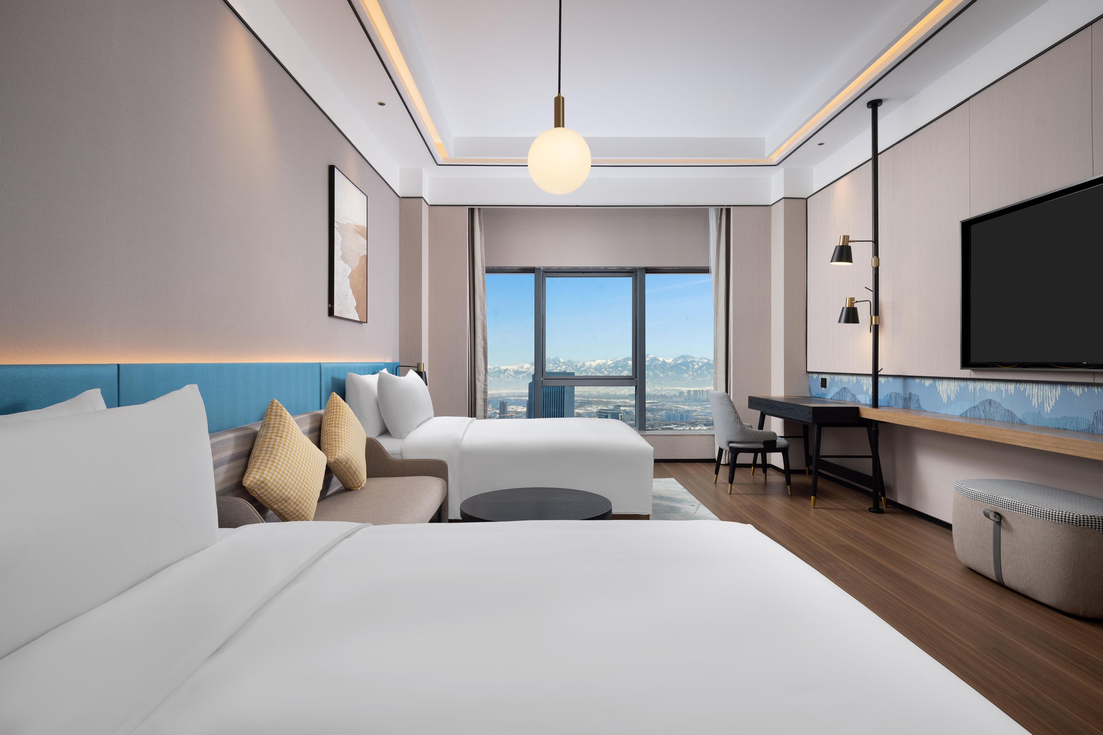 Une chambre d’hôtel moderne avec un grand lit, un bureau et une télévision.