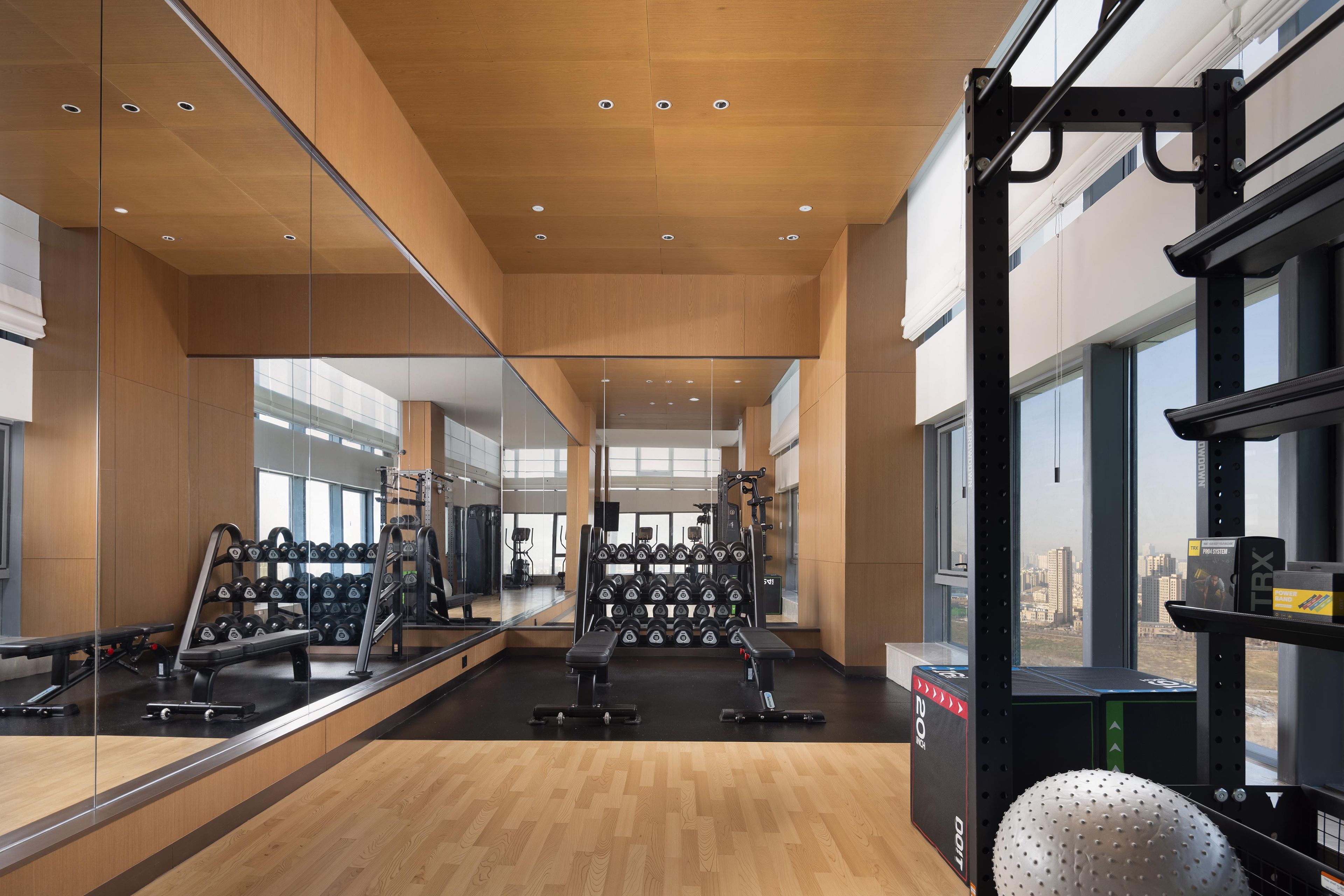 A gym with mirrored walls, weight racks, and exercise equipment.